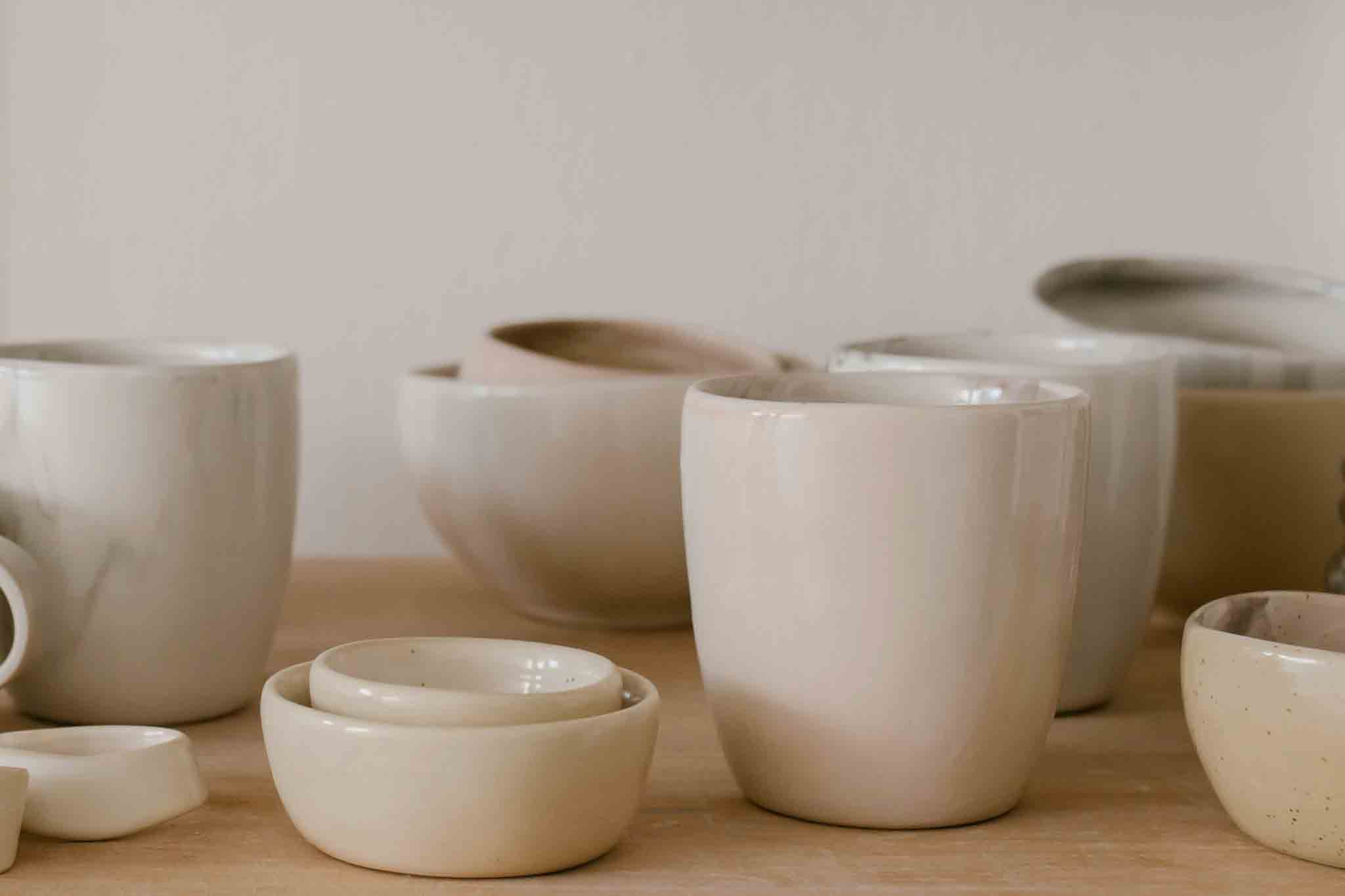 White ceramic pots and bowls displayed on a wooden table post firing.